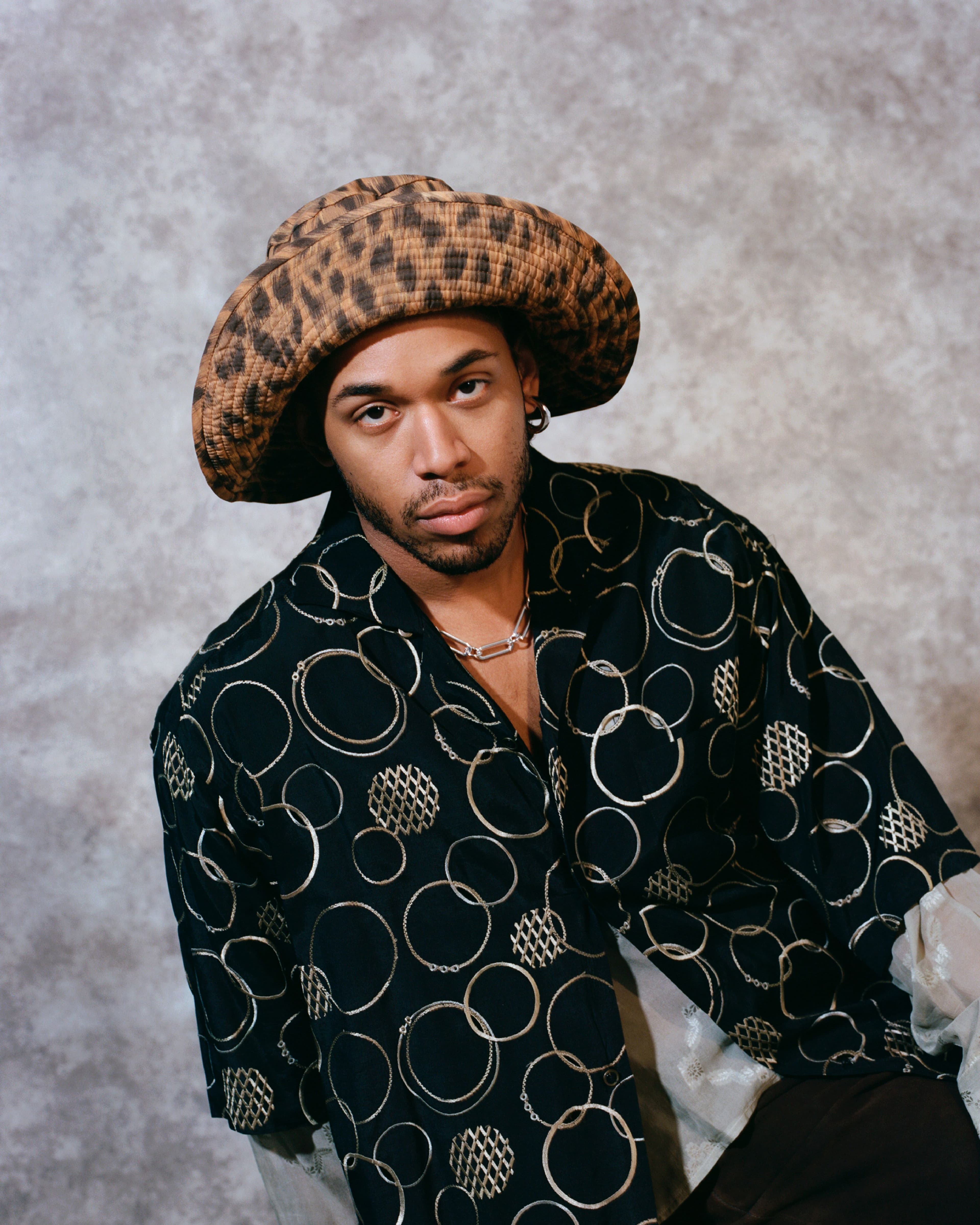 Vintage shirt by Matsuda, stylist’s own. Vintage shirt, worn underneath, by Gucci by Tom Ford, stylist’s own. Vintage pants by Ralph Lauren, stylist’s own. Vintage hat by Moschino from the Albright Fashion Library. Vintage necklace from the Albright Fashion Library.